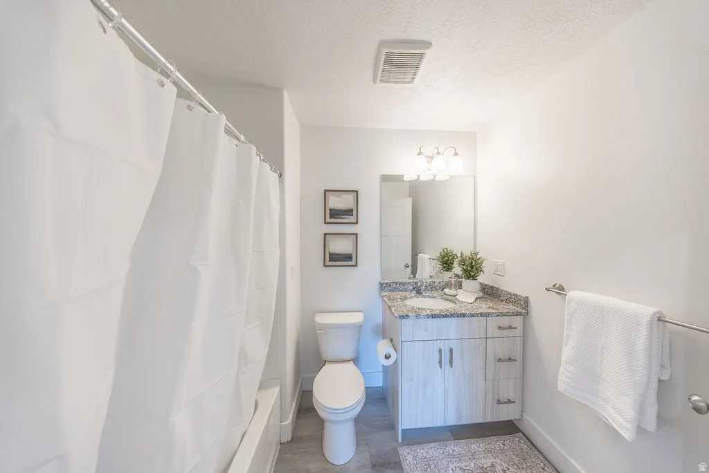 Hall way bathroom #2.  Shower-tub combination, a vanity with a stone-finish countertop, sink, and a wall mirrow.
