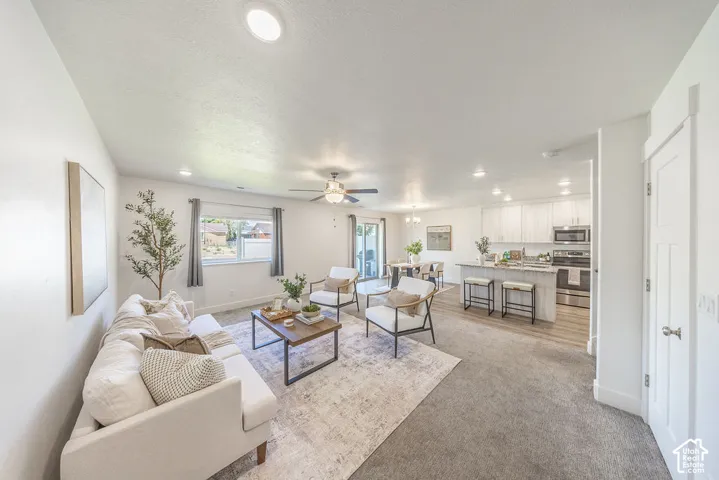 Open-concept living area featuring recessed lighting, a ceiling fan, and light-toned carpeting freshly cleaned.  Spacious.