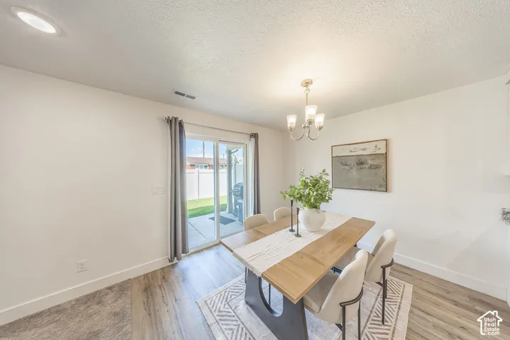 Dining area featuring LVP flooring, a contemporary chandelier, and a sliding glass door providing access to an outdoor patio