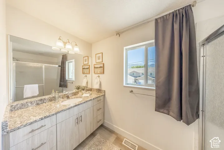 Granite countertop.  Large wall mirror.  Modern light fixture.  Sliding glass doors to shower viewable in mirror.