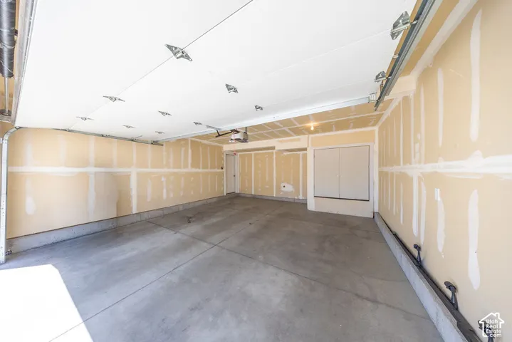 Spacious two-car garage featuring a concrete floor, an overhead door with an automatic opener, and a side access door.  App for garage door opener so you can control it from anywhere.
