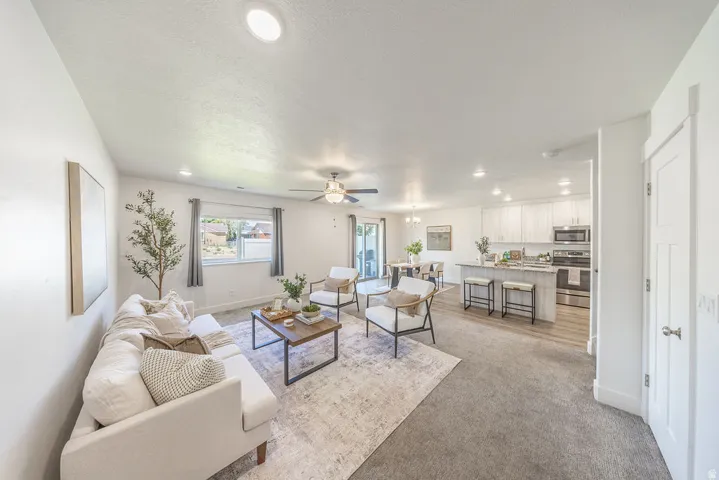 Open-concept living area featuring recessed lighting, a ceiling fan, and light-toned carpeting freshly cleaned.  Spacious.
