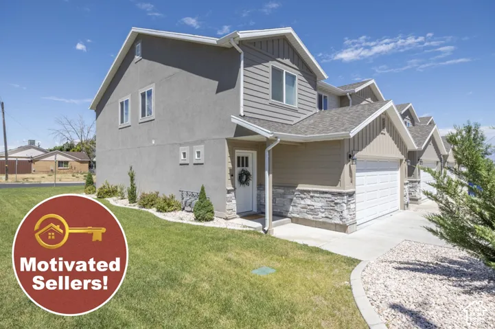 Two-story exterior with stucco and siding elements, stone facade accents, an attached garage, and a concrete driveway