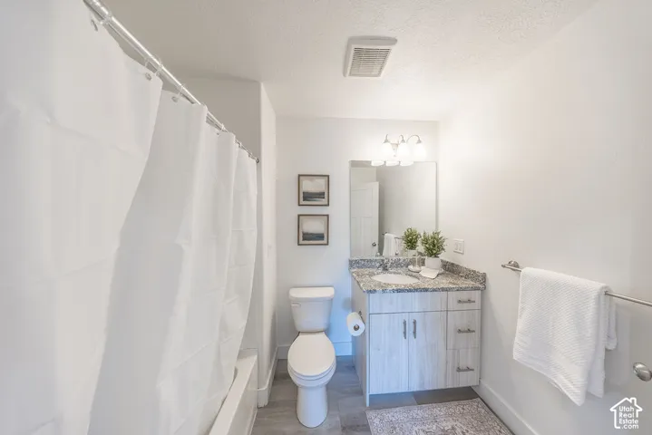 Hall way bathroom #2.  Shower-tub combination, a vanity with a stone-finish countertop, sink, and a wall mirrow.