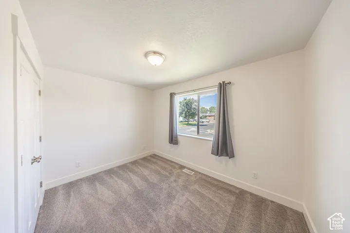 Bedroom #3.  Light wall color.  Light carpet.  Natural light through window.