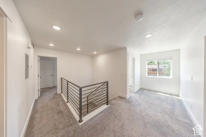 Hallway.  Flex space to the right by window. Light grey carpet.  Natural light.  Recessed lighting.