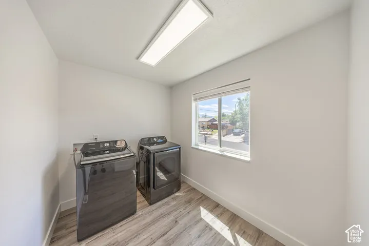 LARGE laundry room with LVP flooring, a window with blinds, and a ceiling-mounted rectangular light fixture