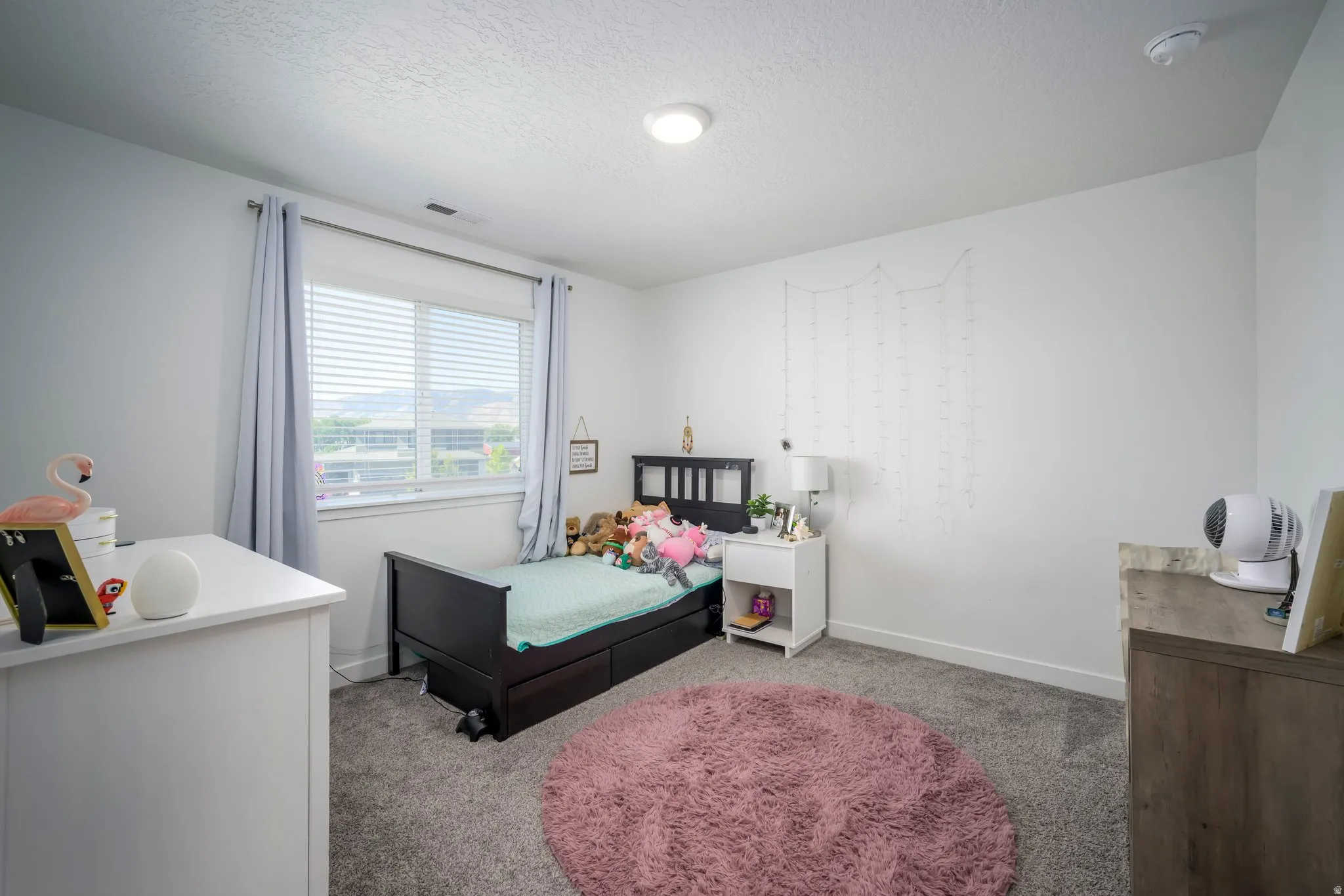 Carpeted bedroom with a window featuring horizontal blinds and drapery