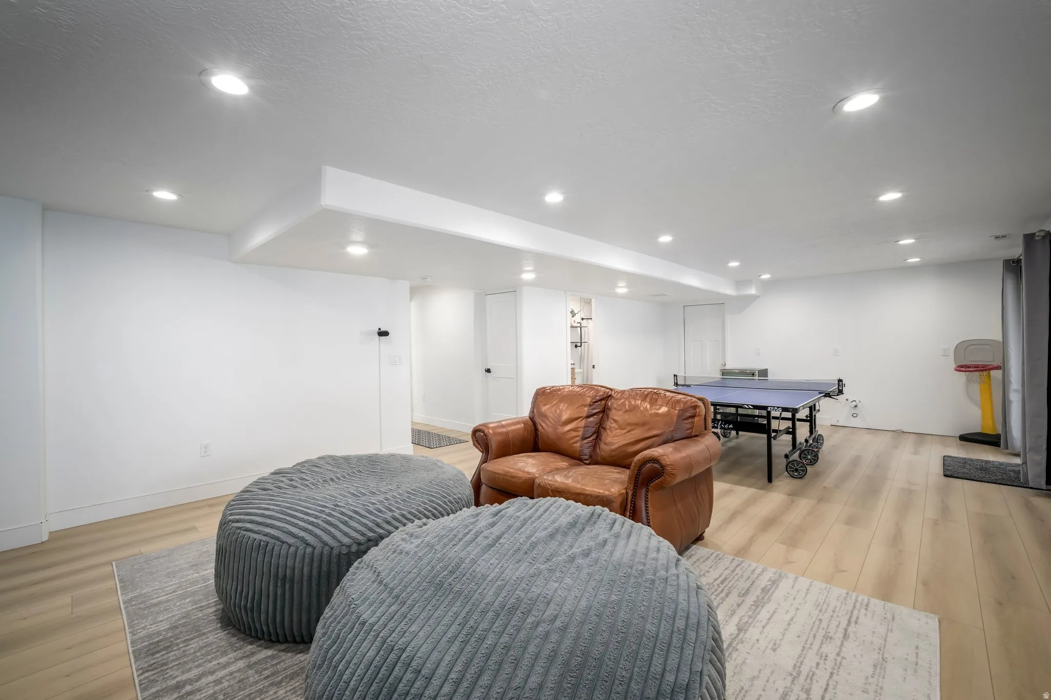 Spacious room featuring recessed lighting, light wood-finish flooring, white walls, and white baseboards