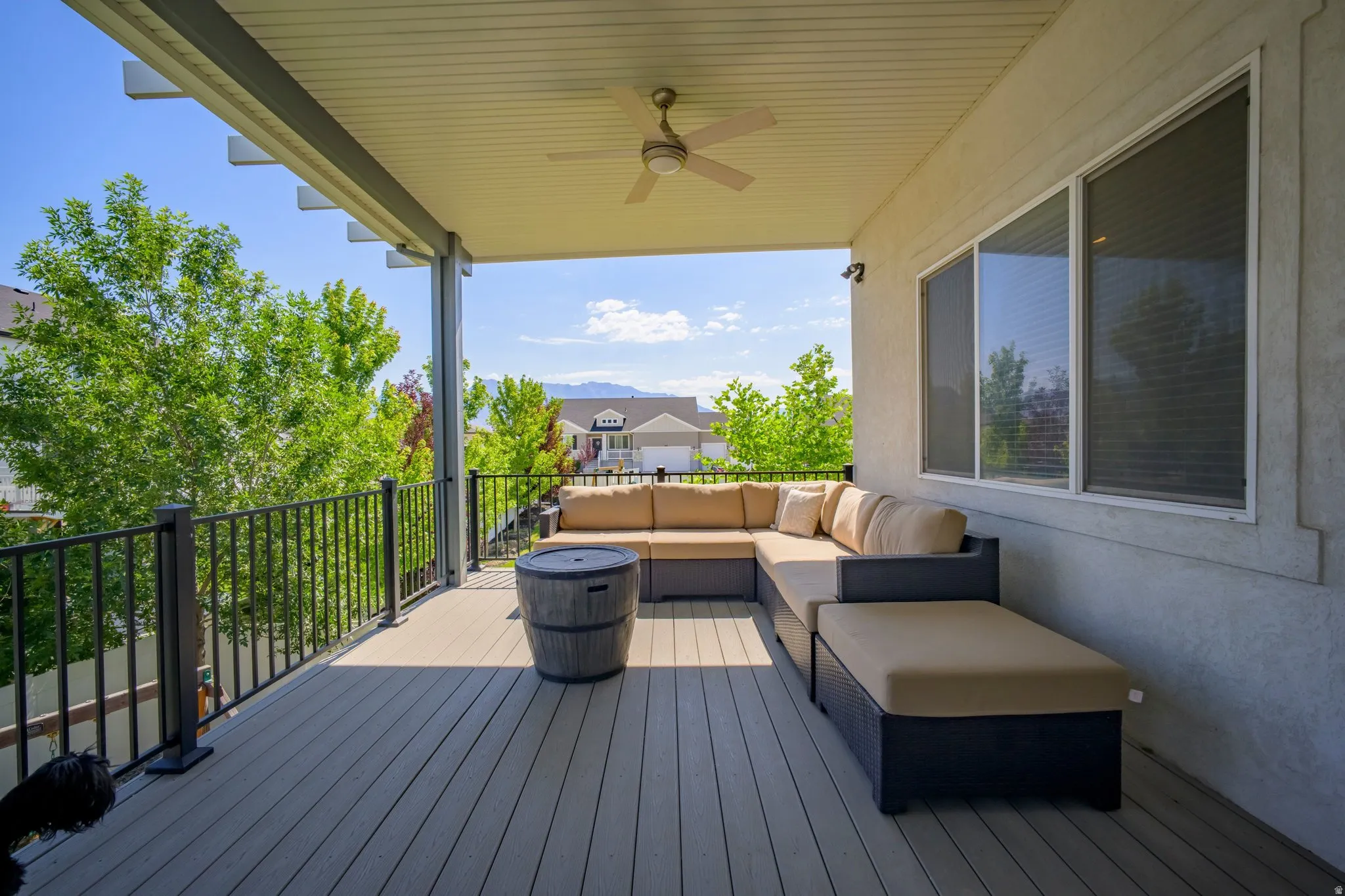 Spacious covered balcony featuring wood-finish decking, black metal railings, and a ceiling fan