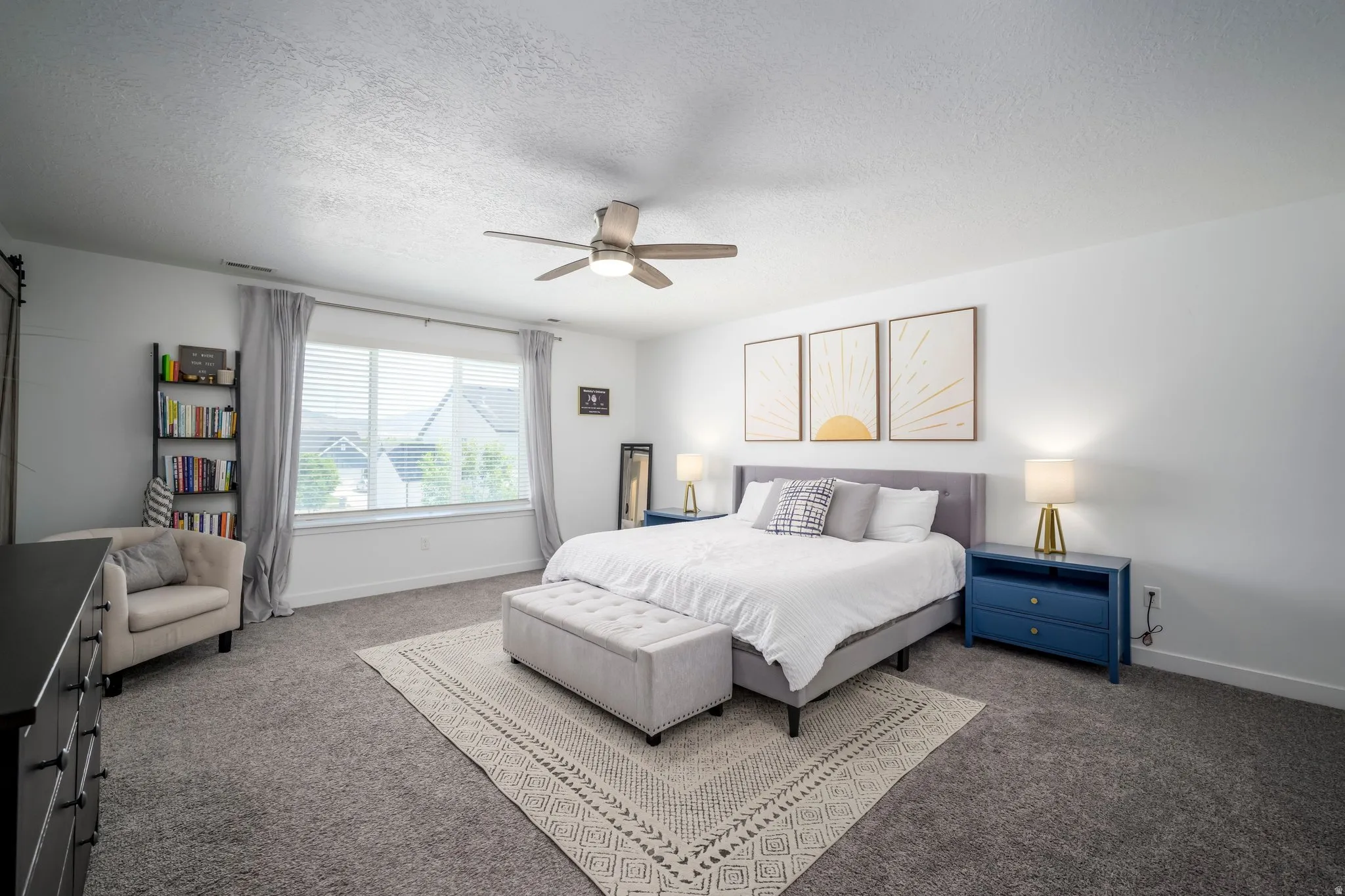 Spacious carpeted room featuring a ceiling fan, a large window with horizontal blinds, and white walls