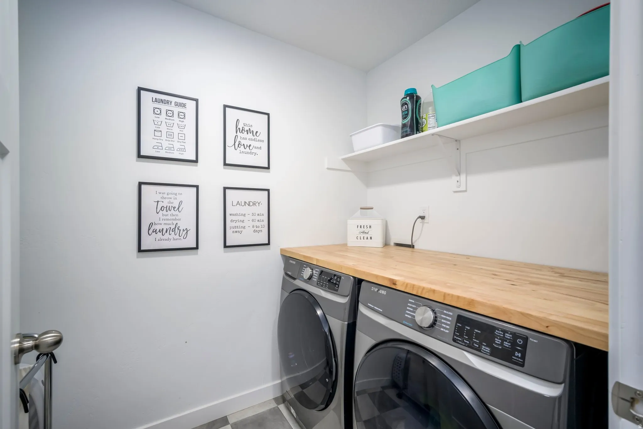 Dedicated laundry area featuring a wood-finish countertop, white walls, and built-in shelving