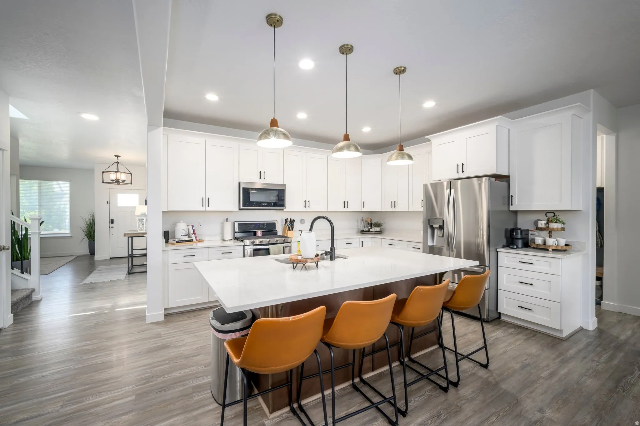 Modern kitchen featuring white cabinetry, stainless steel appliances, and a central island with a light-toned countertop