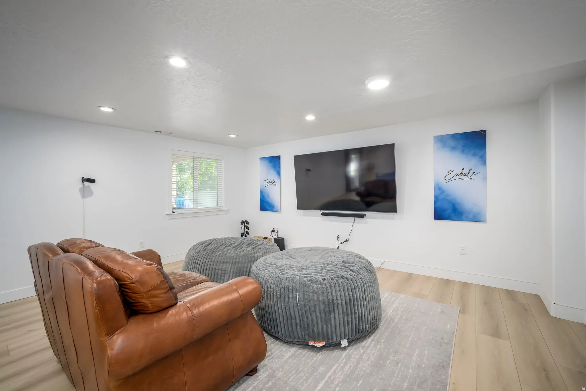 Spacious room featuring light wood-finish flooring, recessed lighting, and a neutral color palette