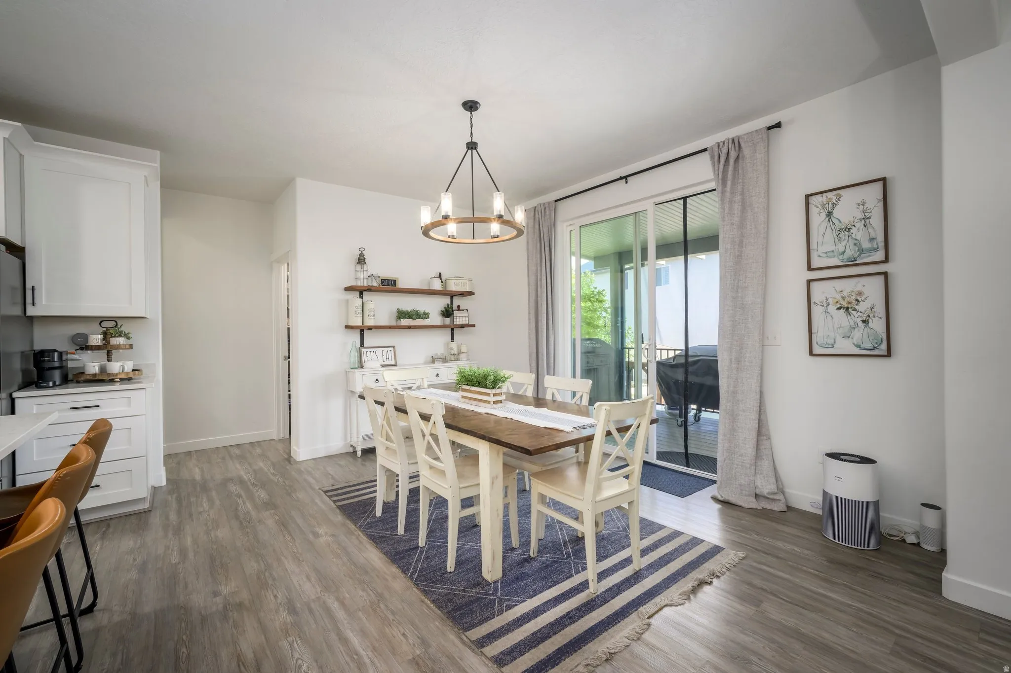 Open-concept dining area featuring wood-finish flooring, a contemporary chandelier, and a sliding glass door providing access to an outdoor area