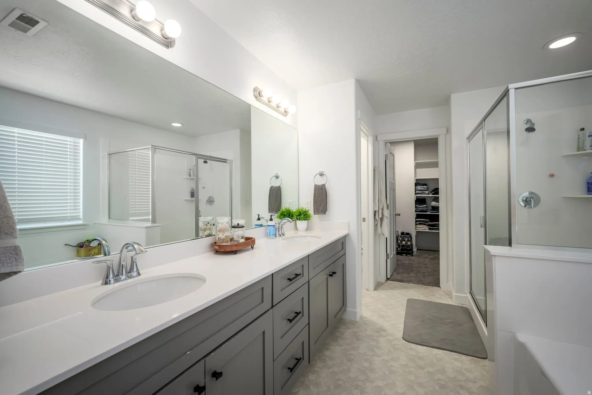 Dual vanity with white countertops, undermount sinks, and gray cabinetry