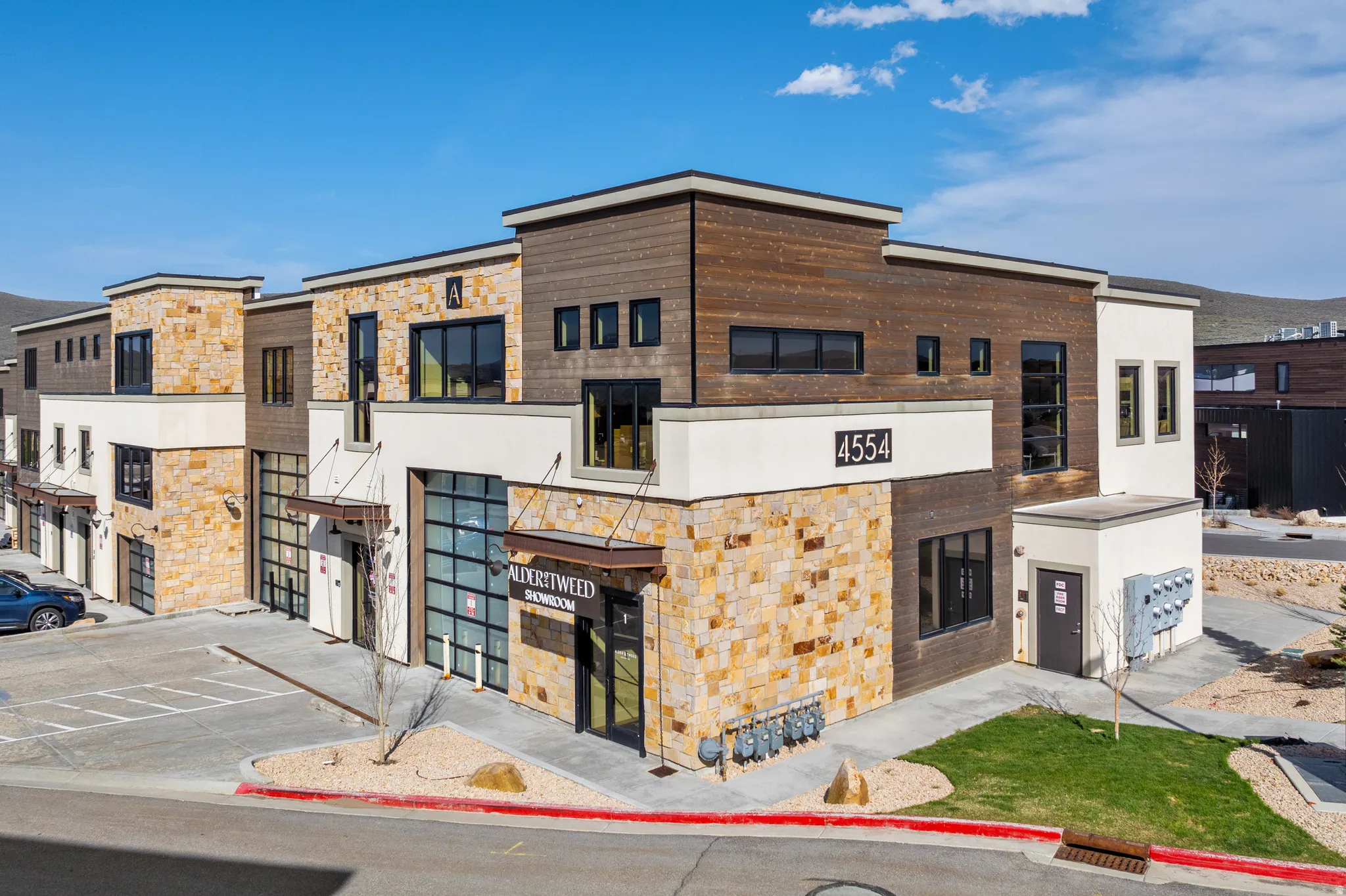Modern commercial building featuring stone veneer, horizontal wood-finish siding, and stucco accents