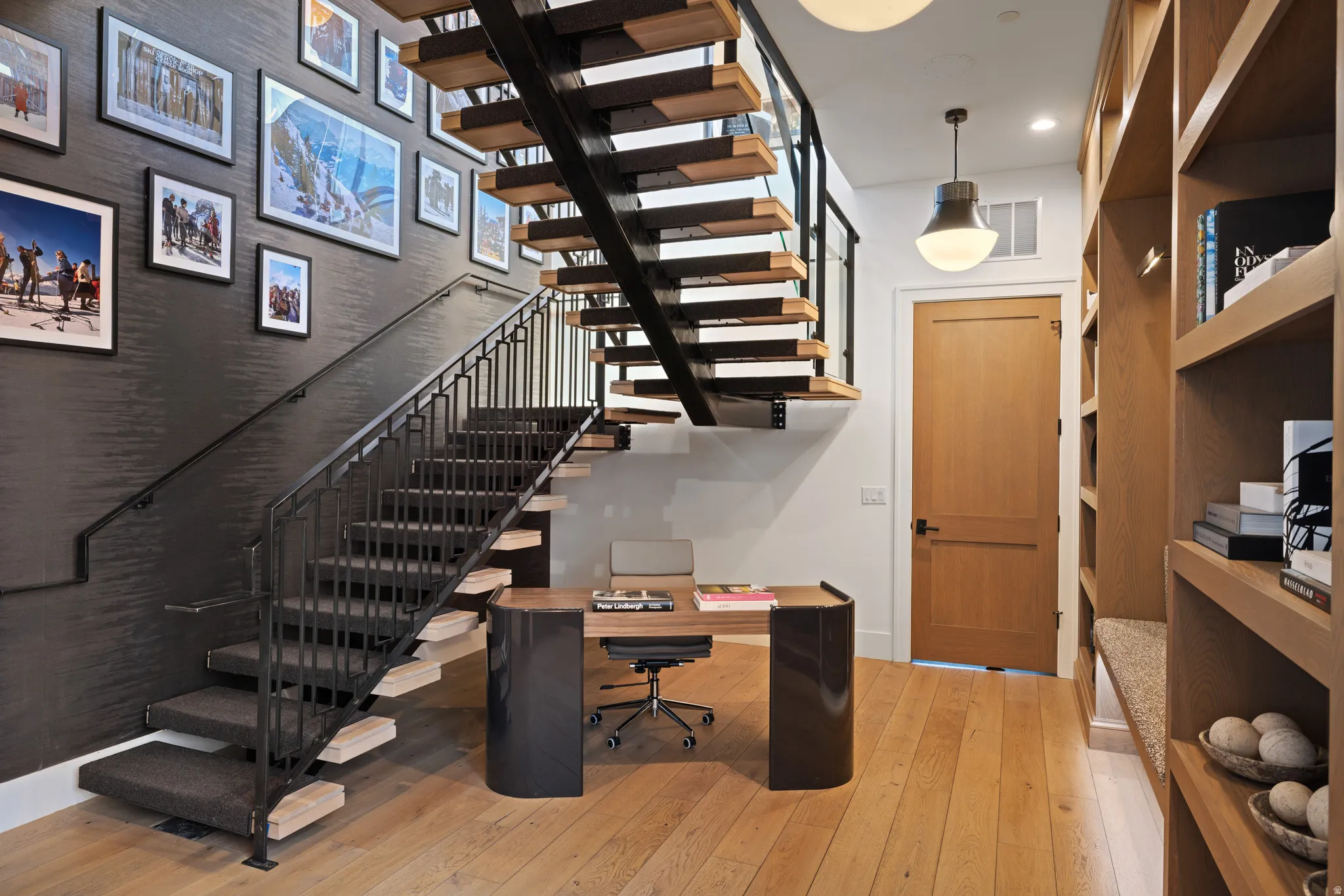 Open-riser staircase with a black metal railing and carpeted treads, complemented by a built-in wood-finish desk