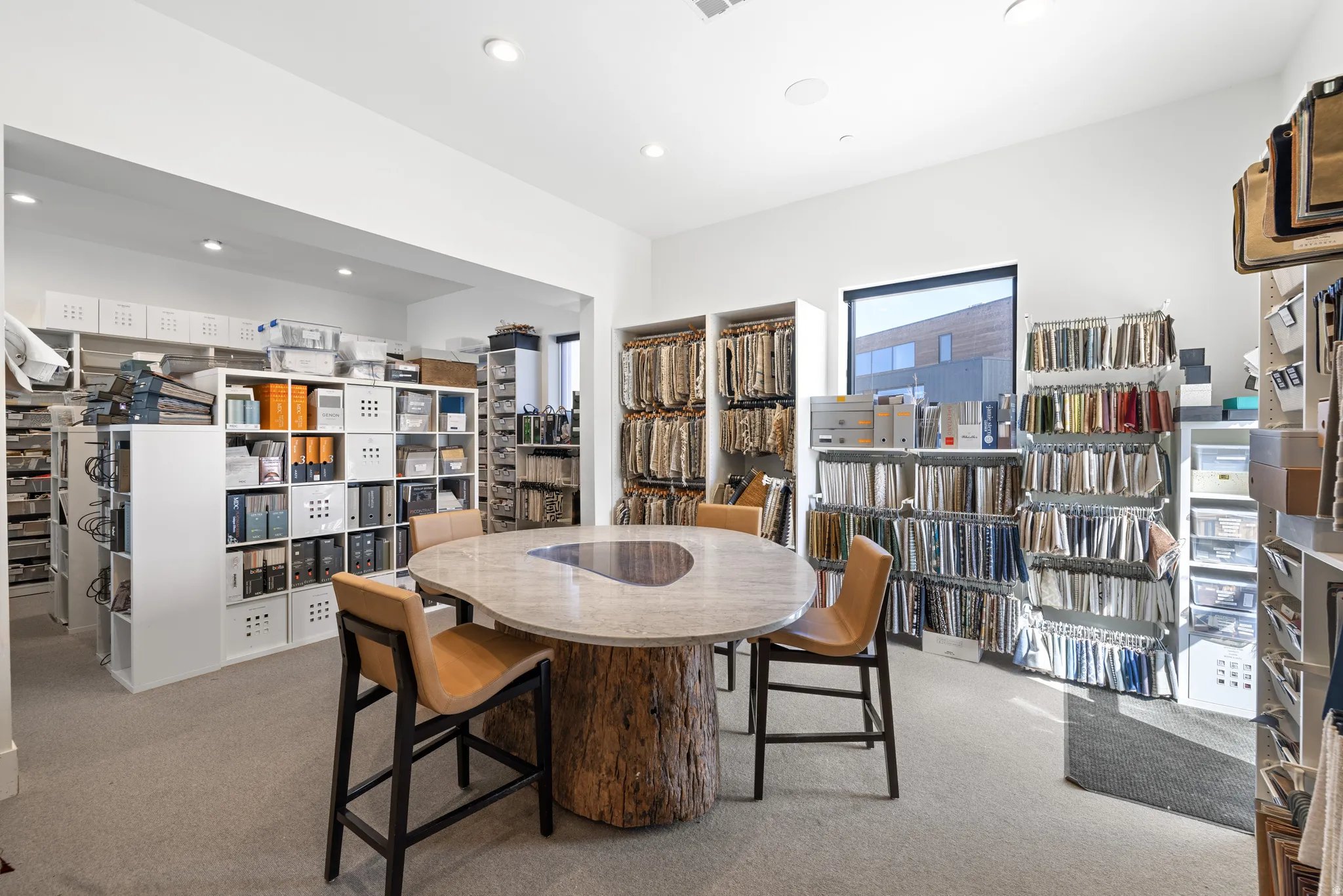 Spacious room featuring neutral carpeting and a central wood-base table with a stone top
