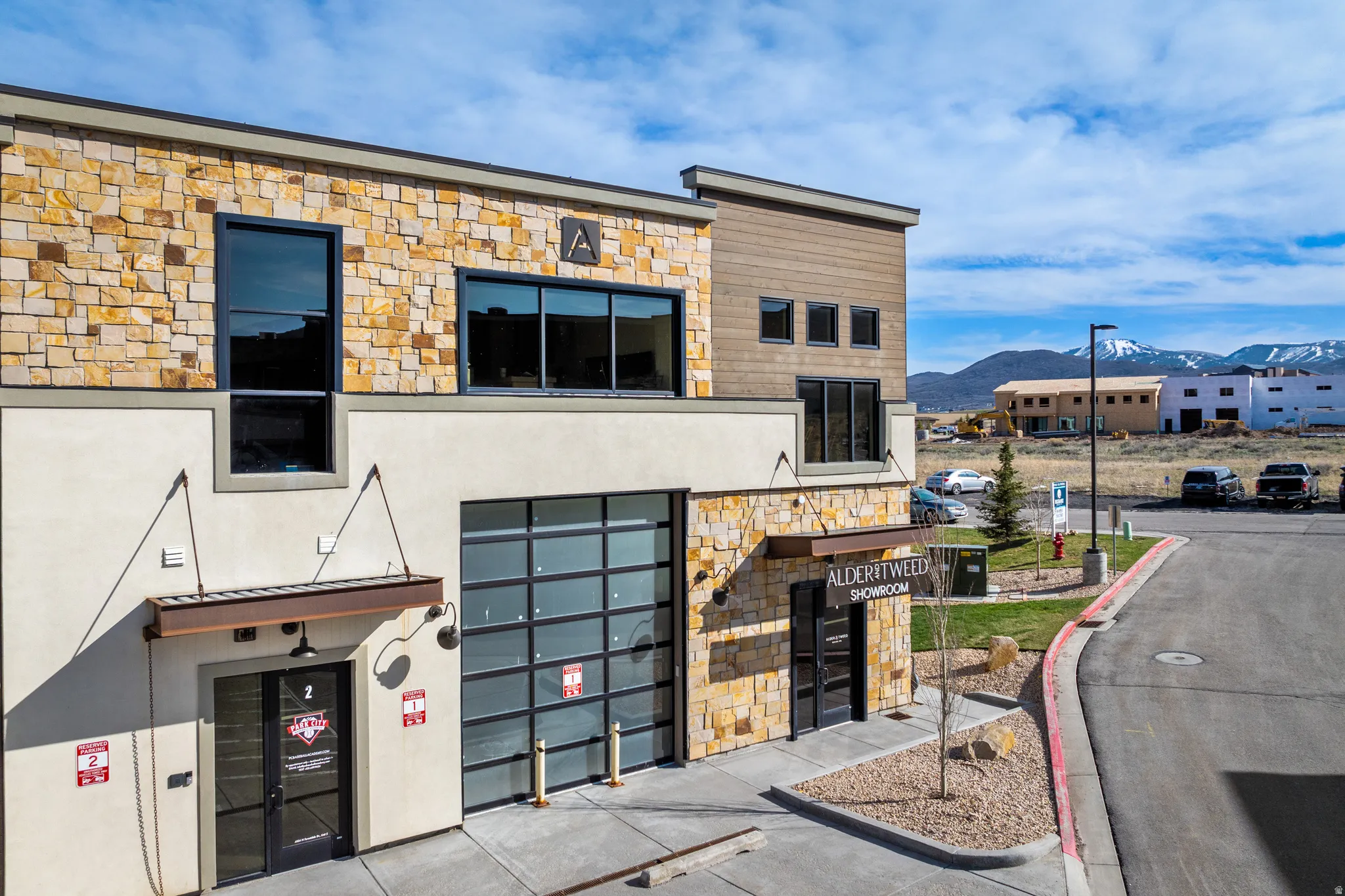 Modern commercial building featuring a stone and stucco facade, a glass overhead door, and storefront entryways