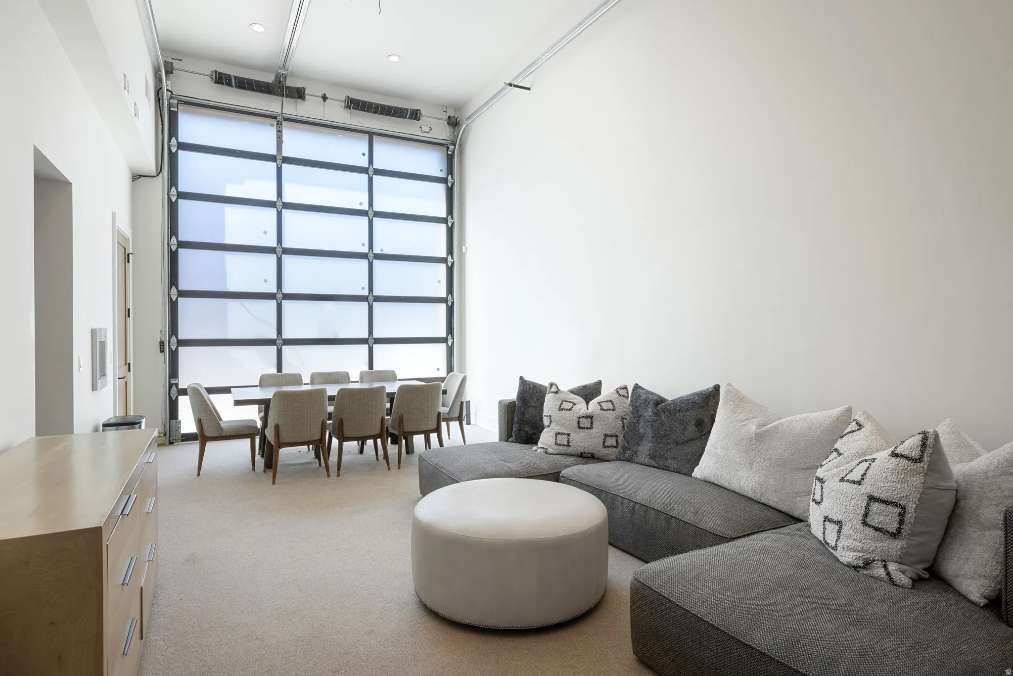 Expansive room featuring a roll-up glass garage door, high ceilings with exposed tracks, and light-toned wall finishes
