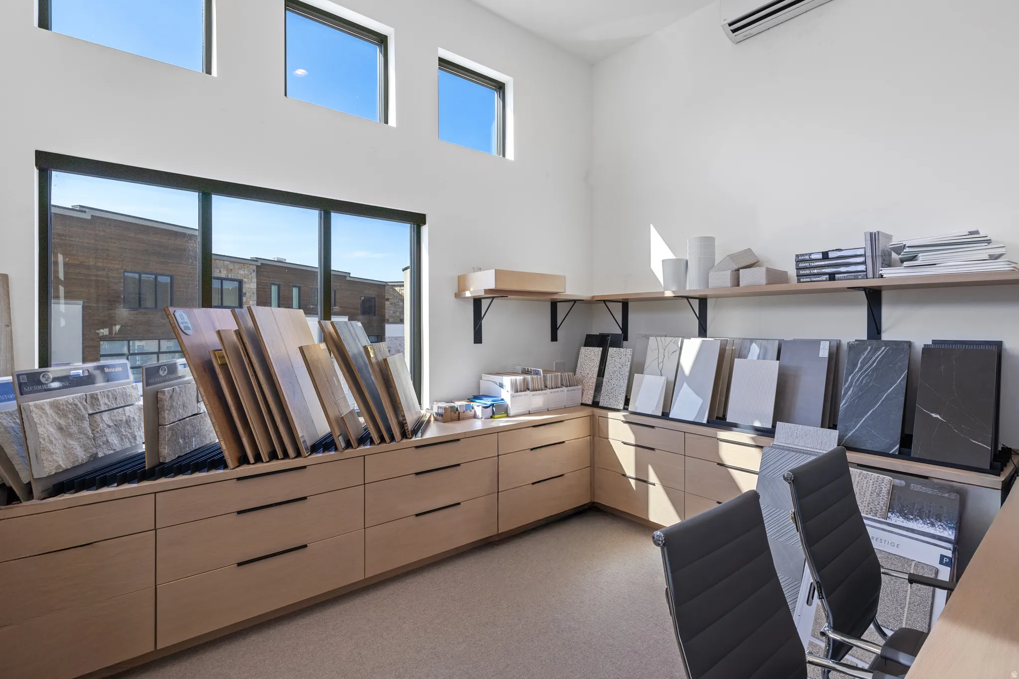 Spacious interior featuring extensive custom wood-finish cabinetry with black hardware, large-format windows, high ceilings, and an overhead climate control unit