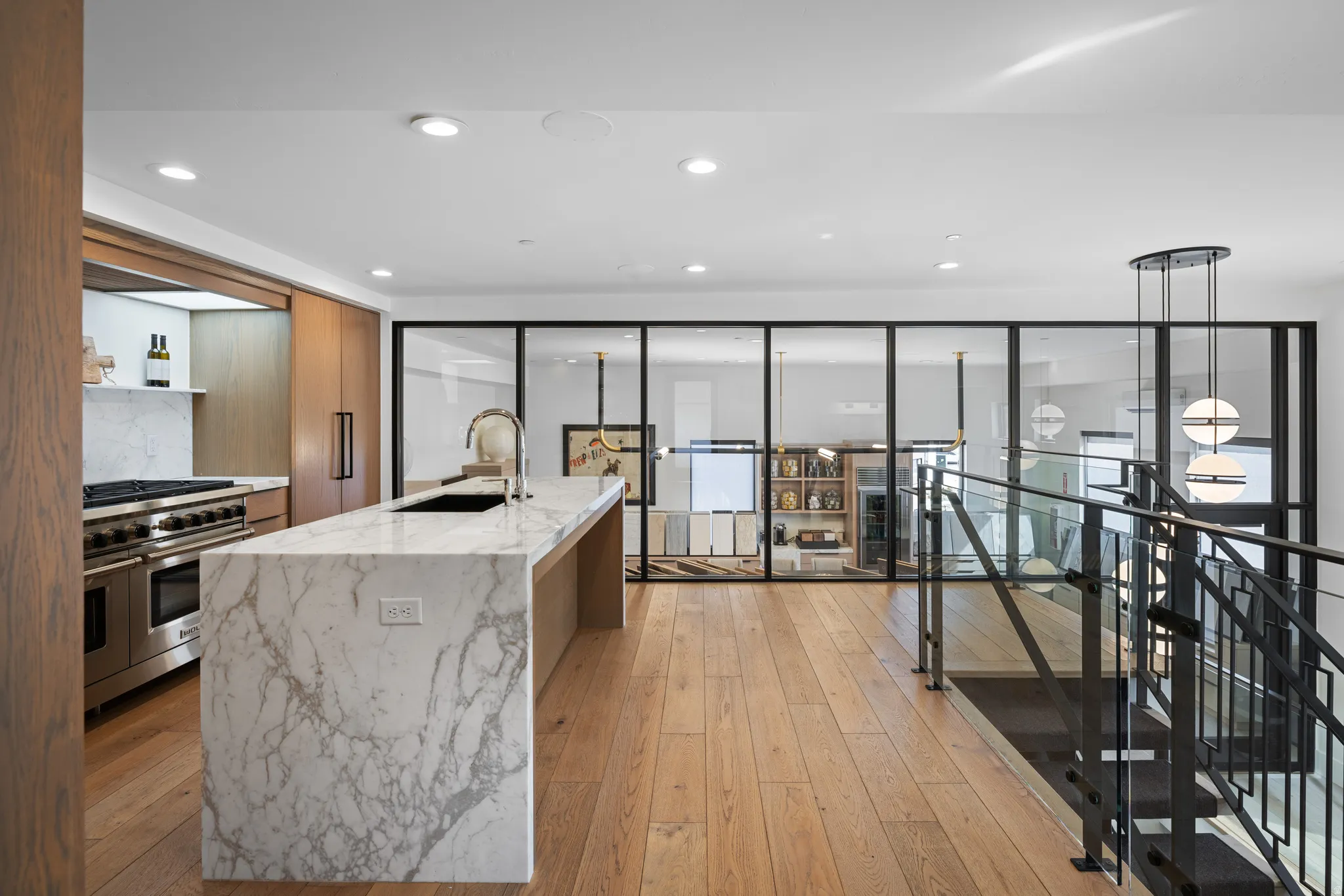 Open-concept kitchen featuring an oversized stone island with waterfall edges and an undermount sink