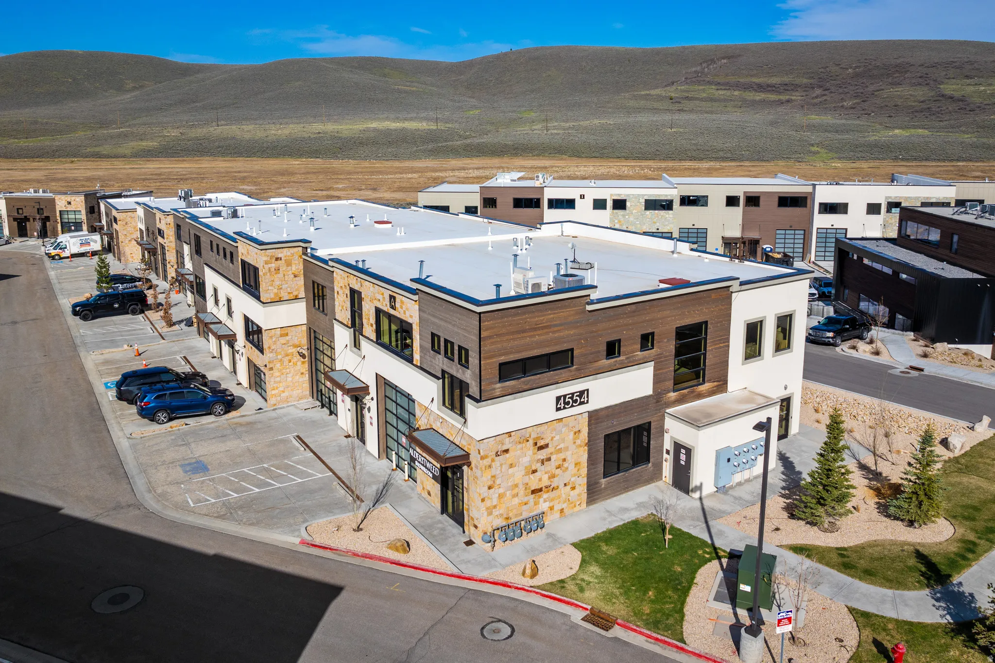 Modern commercial building featuring stone veneer, wood-finish siding, large windows, and multiple entry points