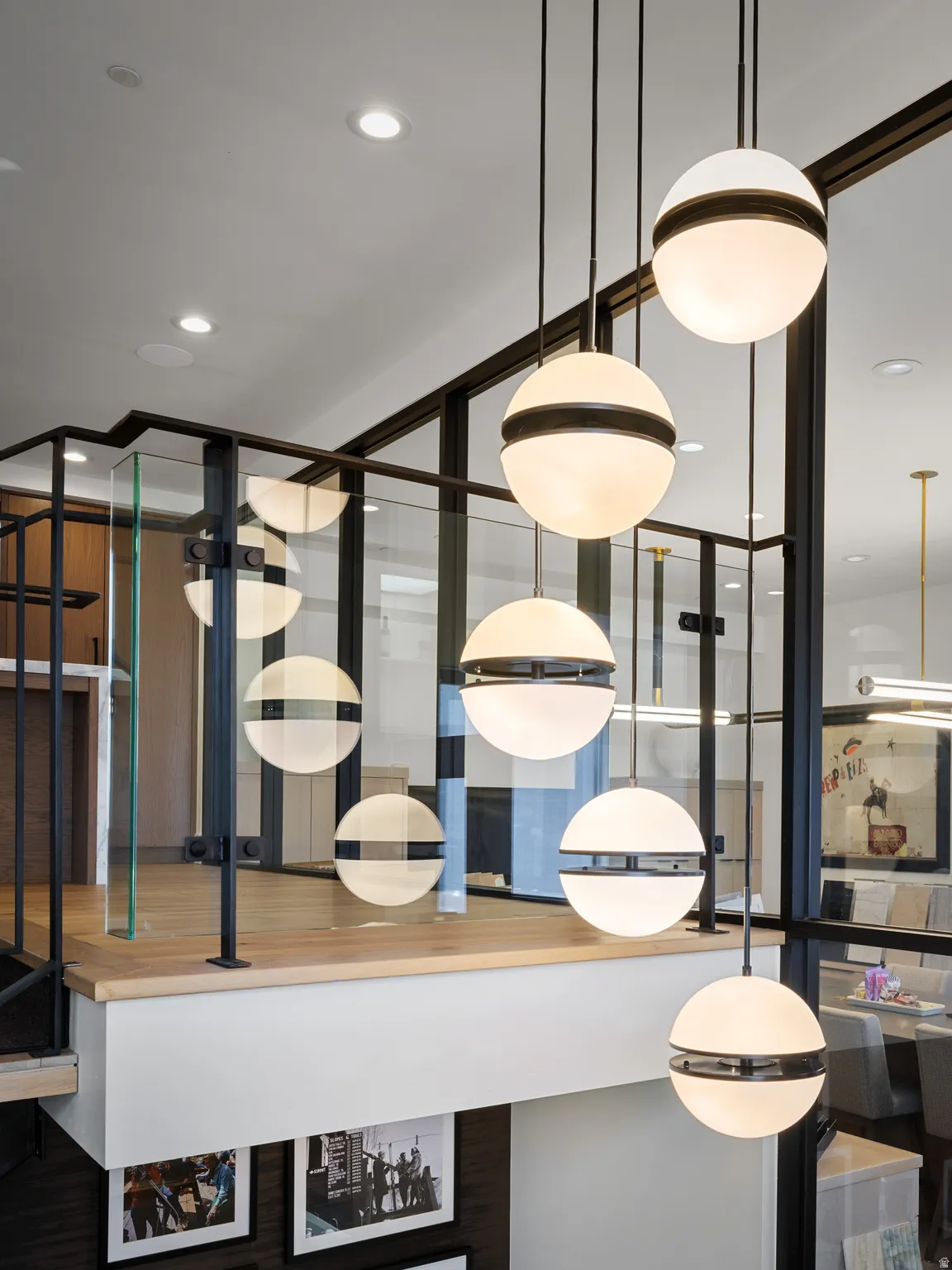 Modern spherical pendant lights illuminate a landing featuring a glass and black metal railing system