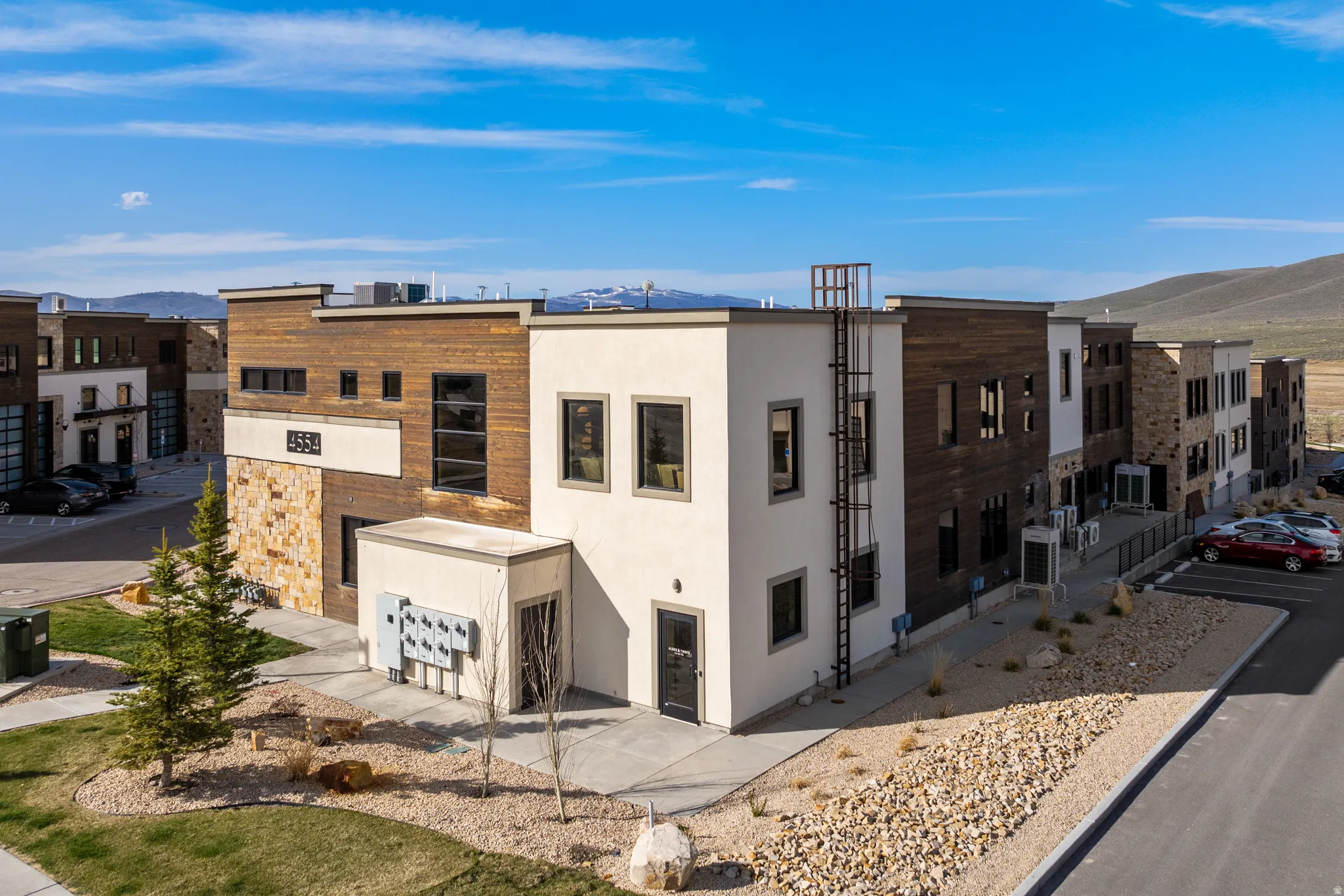 Modern multi-story building featuring a facade with mixed materials including stucco, wood-look siding, and stone accents