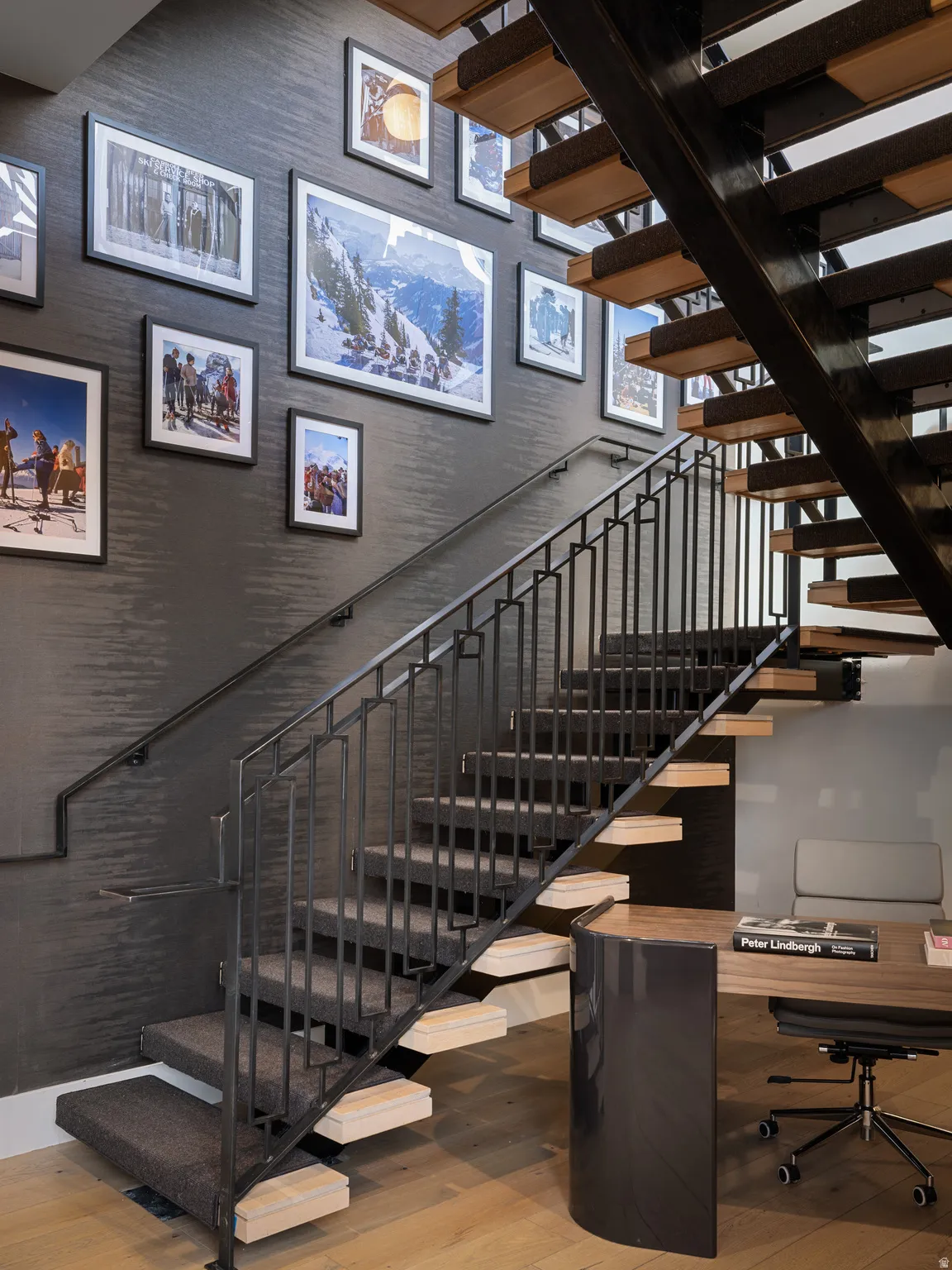 Floating staircase with wood-finish treads and metal railings, set against a textured wall covering