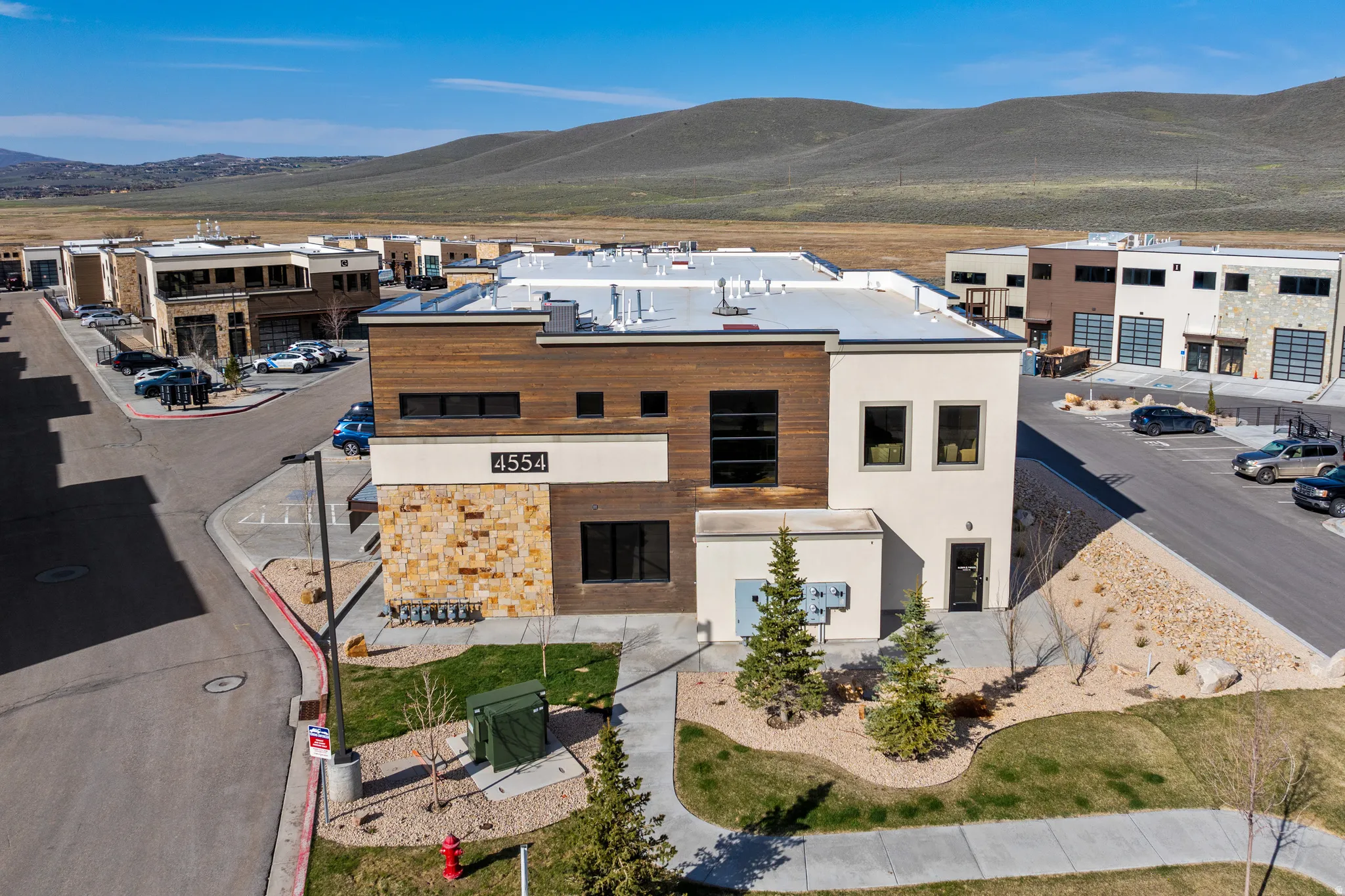 Contemporary building exterior featuring a stone accent wall, wood-finish siding, and multiple large windows