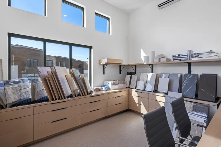 Spacious interior featuring extensive custom wood-finish cabinetry with black hardware, large-format windows, high ceilings, and an overhead climate control unit