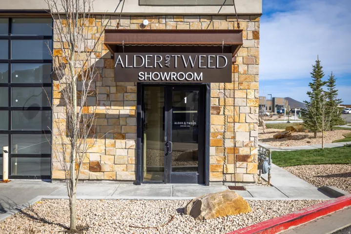 Stone facade commercial property featuring a prominent entrance with a dark-framed glass door, a metal awning, and clear signage