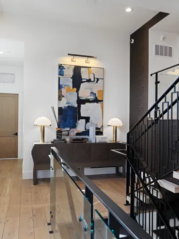 Entryway featuring wood-finish flooring, a dark wood console table, and a contemporary glass and metal staircase railing