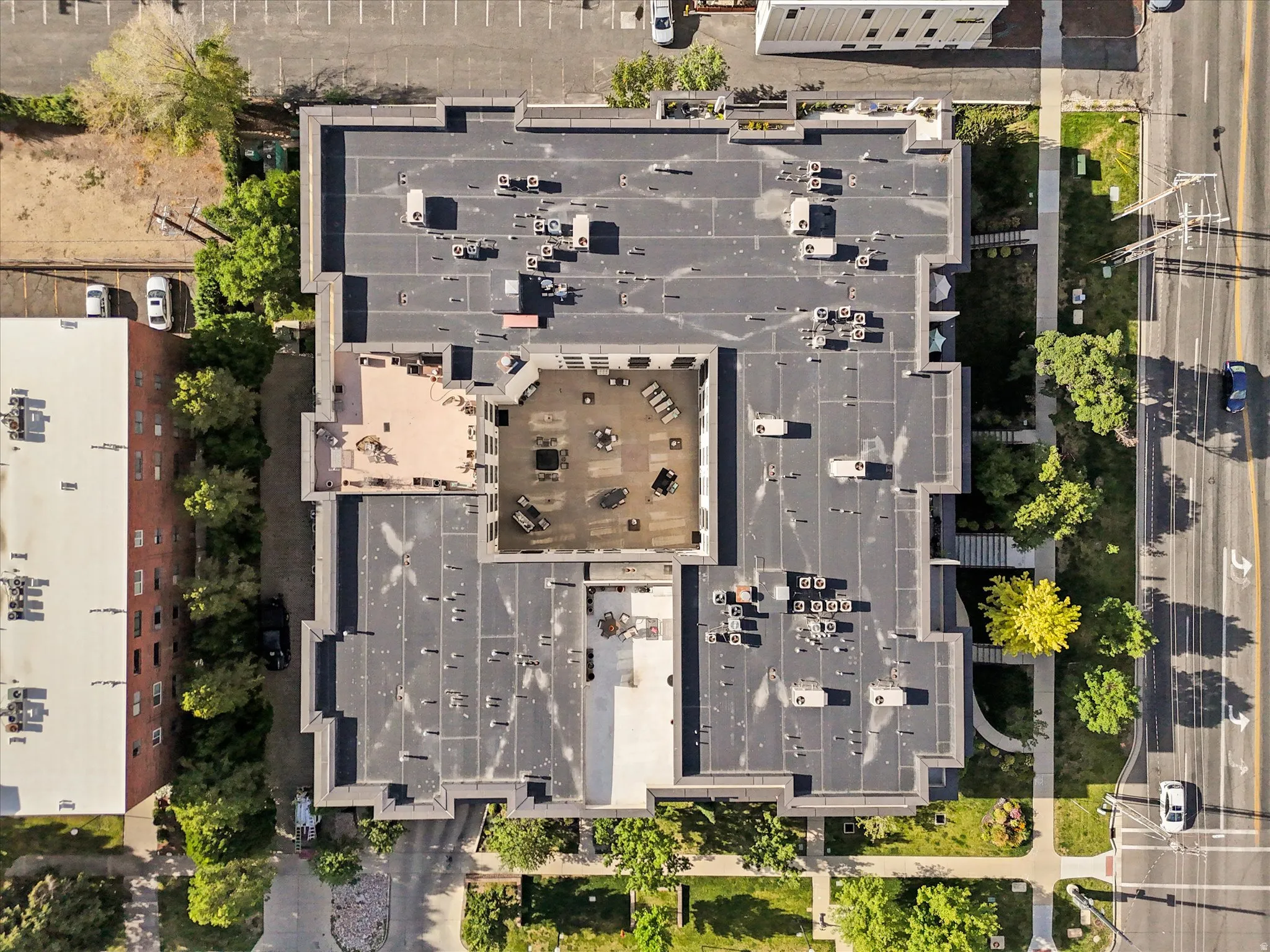 Multi-story building featuring a flat roofline, an interior courtyard, and multiple rooftop patio areas