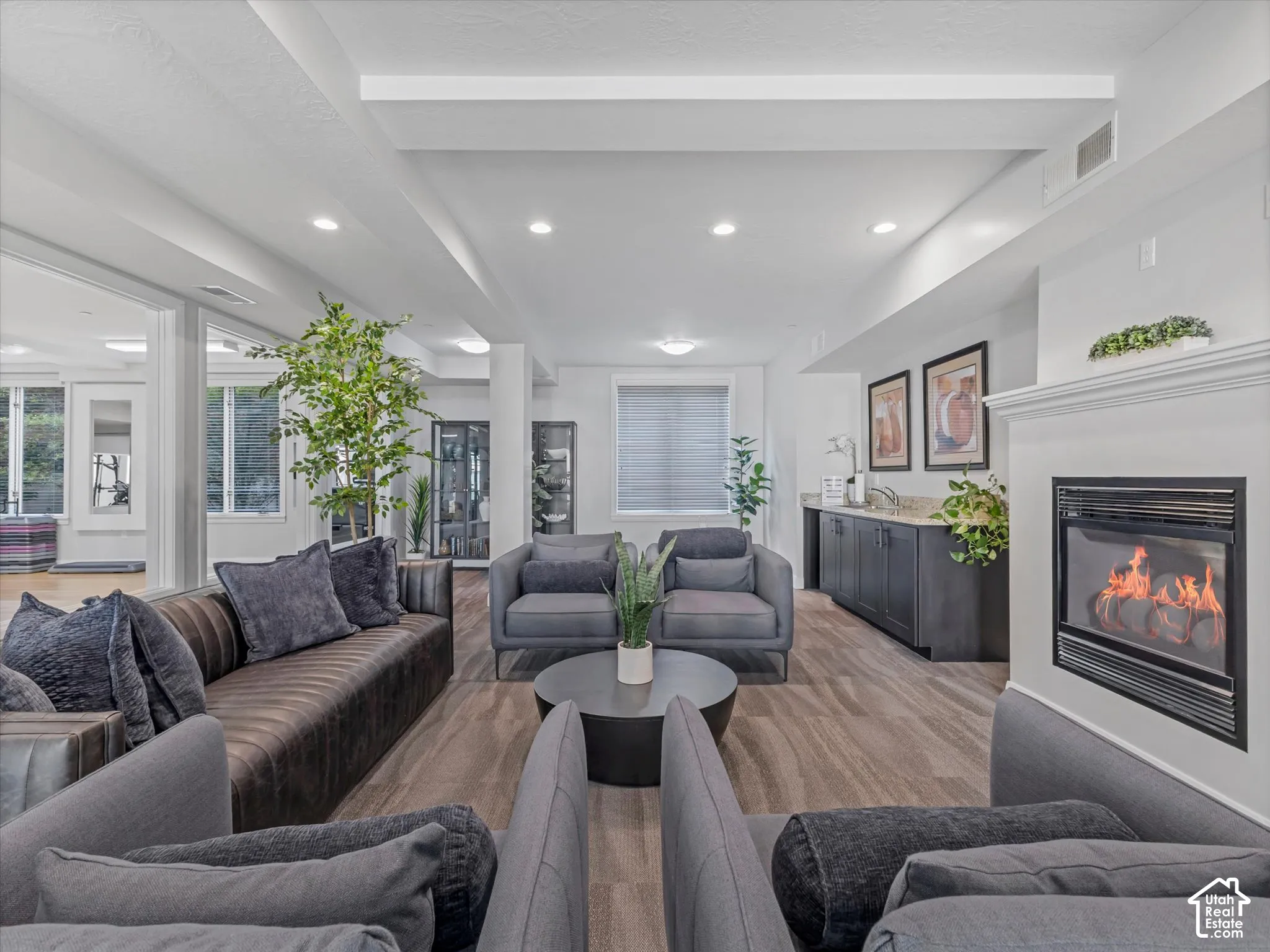 Spacious gathering area featuring wood-finish flooring, recessed lighting, and a white mantel with an inset fireplace