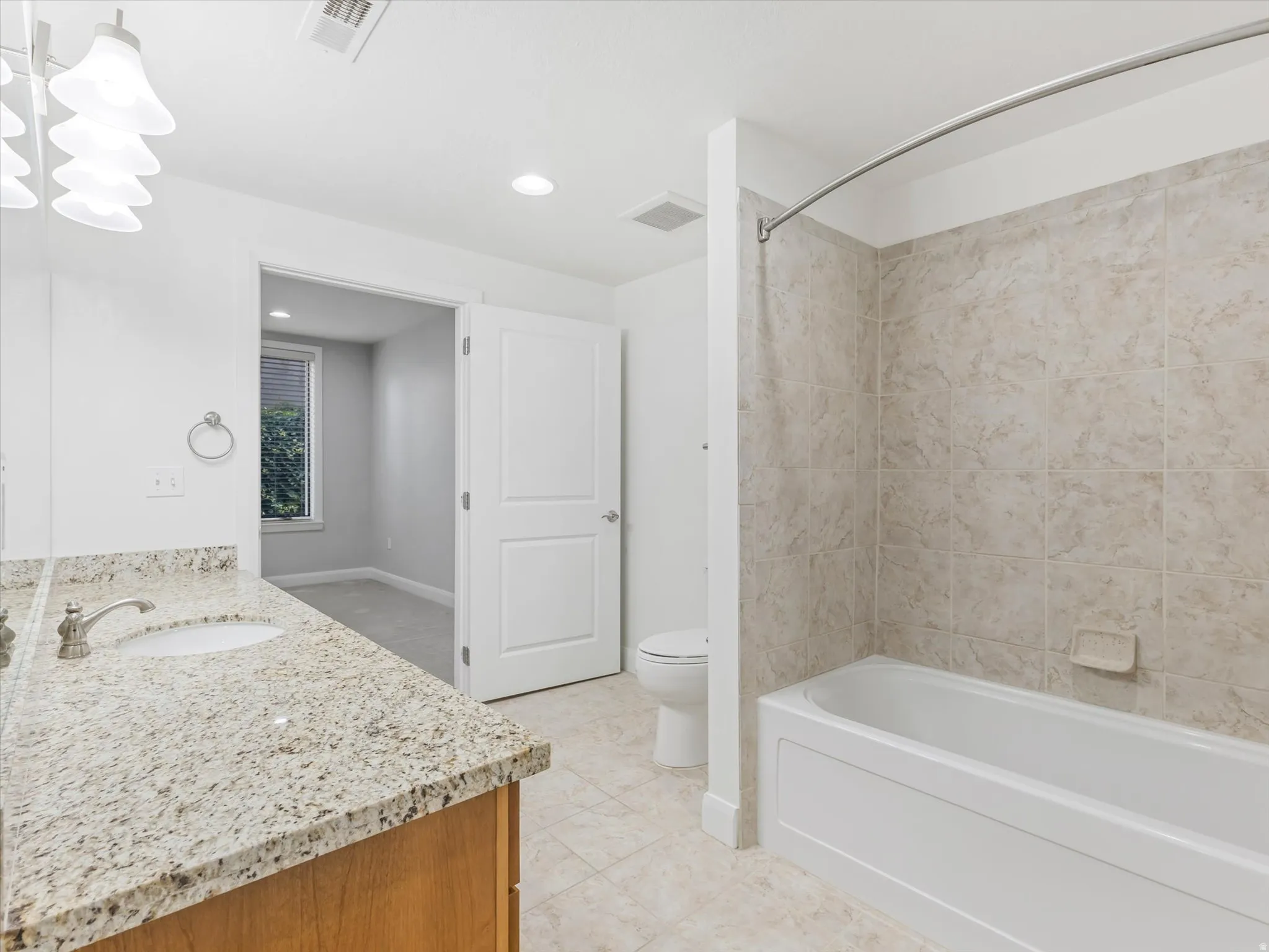 Bathroom featuring a vanity with a light-toned granite countertop and an undermount sink