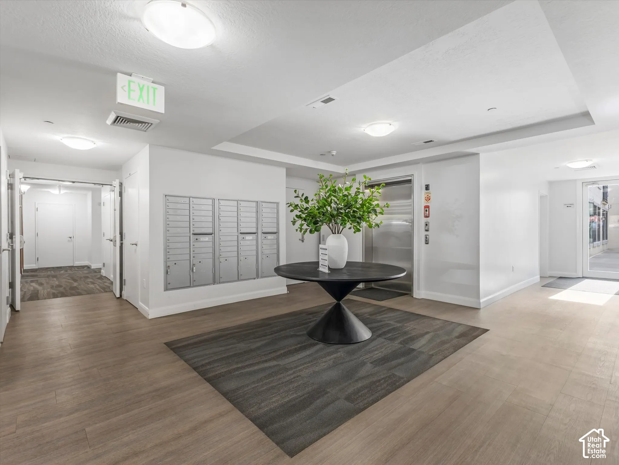 Building lobby featuring wood-finish flooring, recessed lighting, and a wall of individual mailboxes
