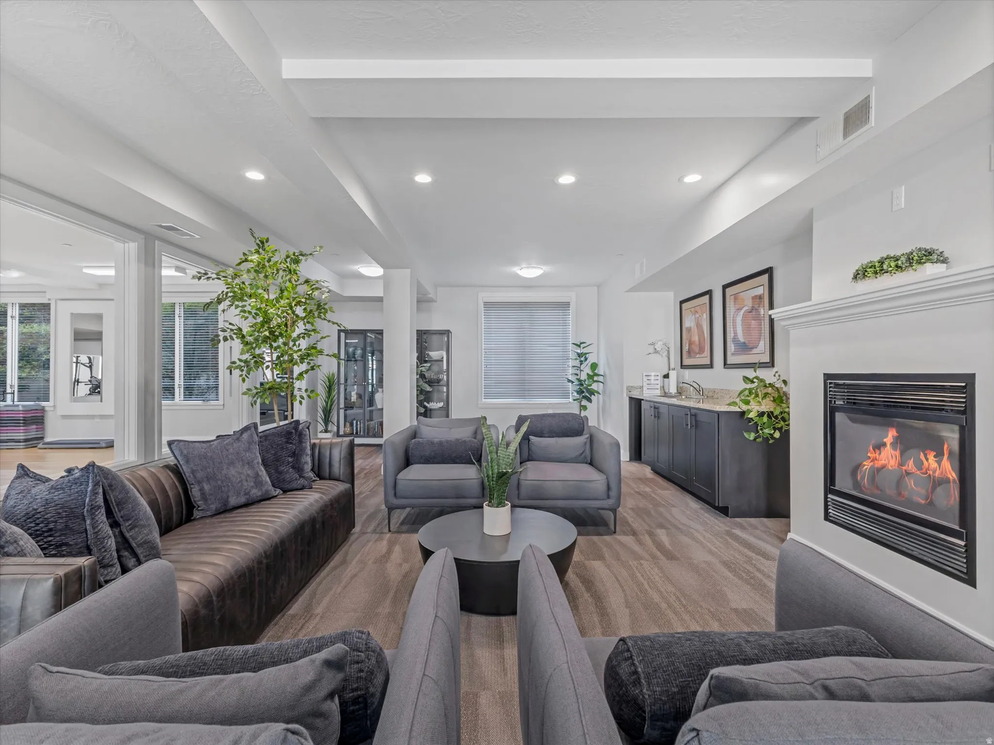 Spacious gathering area featuring wood-finish flooring, recessed lighting, and a white mantel with an inset fireplace