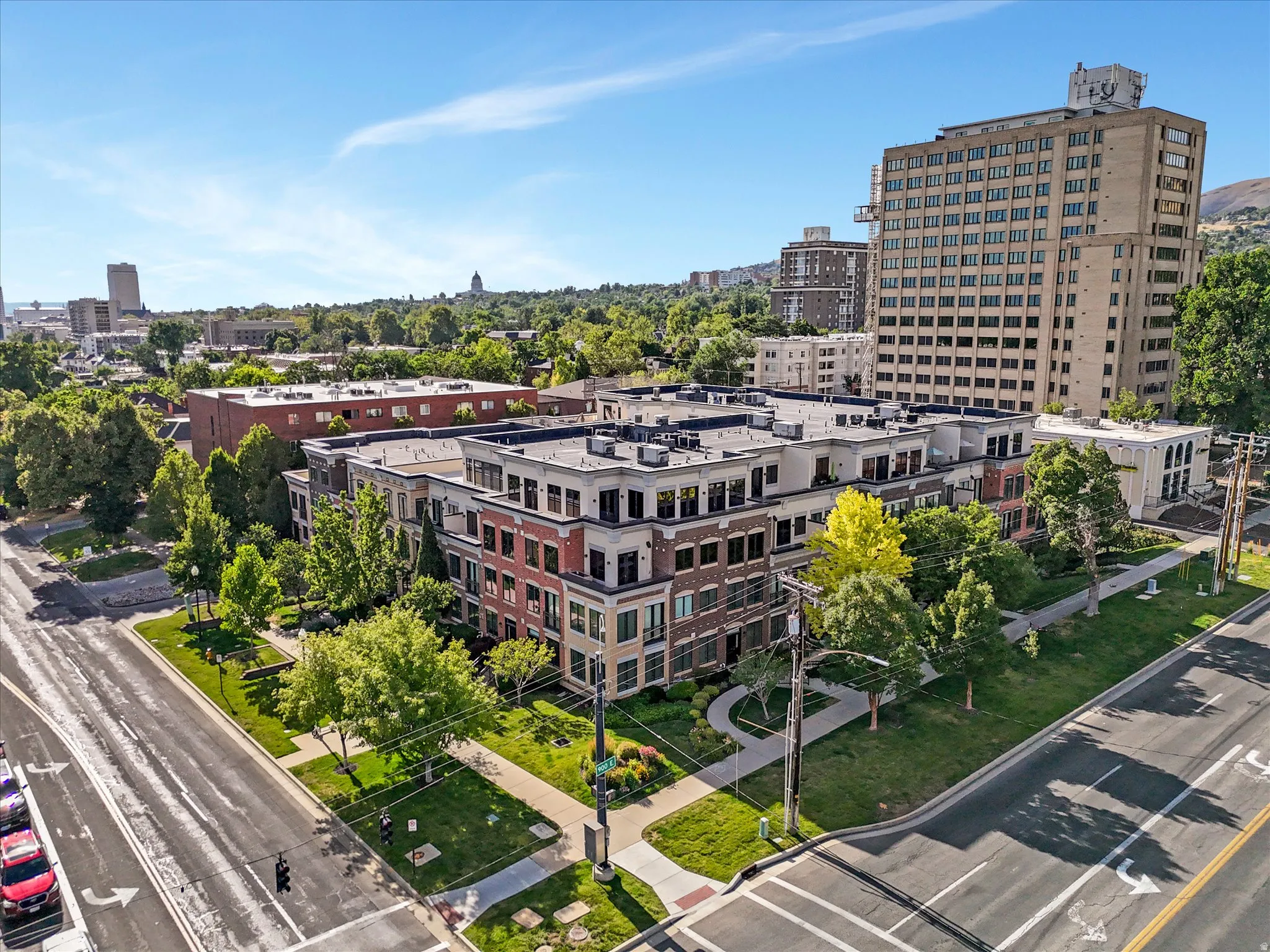 Modern multi-story residential building featuring a brick and stone facade, flat roofline, and integrated landscaping