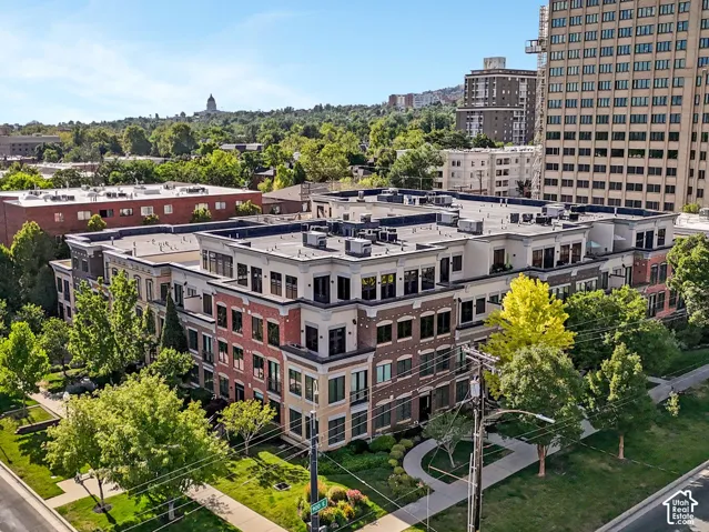 Modern multi-story residential building featuring a brick and stone facade, flat roofline, and integrated landscaping