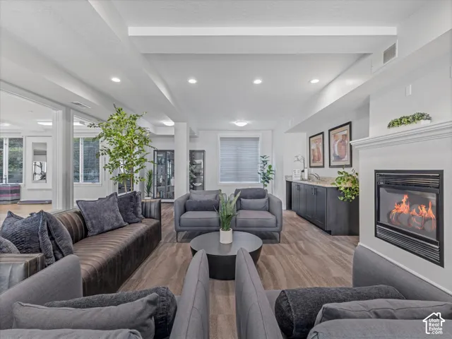 Spacious gathering area featuring wood-finish flooring, recessed lighting, and a white mantel with an inset fireplace