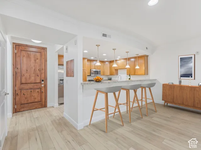Open-concept kitchen and living area featuring wood-finish flooring, recessed lighting, and a kitchen island with granite-style countertop