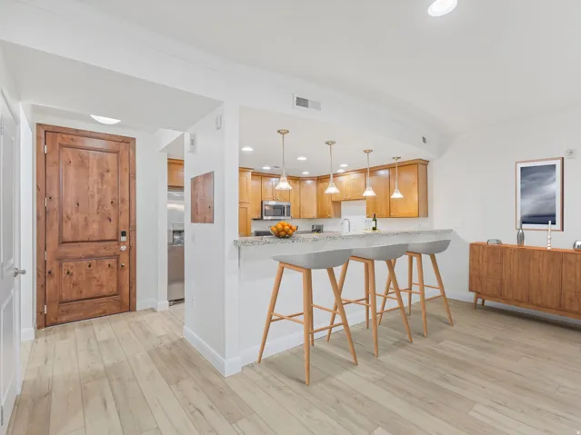 Open-concept kitchen and living area featuring wood-finish flooring, recessed lighting, and a kitchen island with granite-style countertop