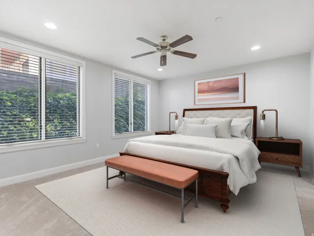 Spacious room featuring two large windows with blinds, recessed lighting, and a ceiling fan