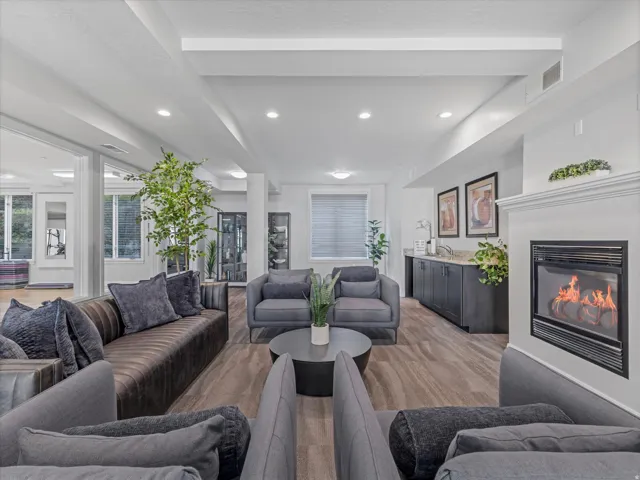 Spacious gathering area featuring wood-finish flooring, recessed lighting, and a white mantel with an inset fireplace