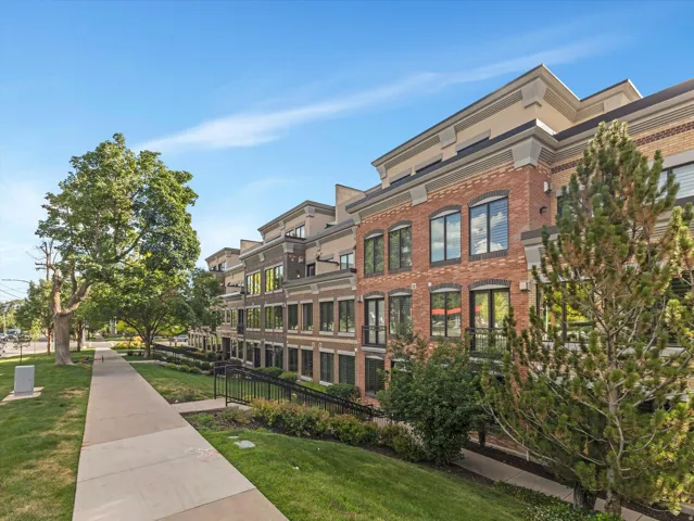 Brick and stucco facade townhouse featuring a multi-story design with prominent windows