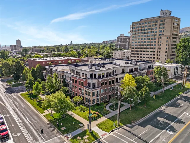 Modern multi-story residential building featuring a brick and stone facade, flat roofline, and integrated landscaping