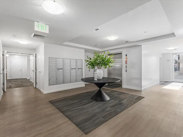 Building lobby featuring wood-finish flooring, recessed lighting, and a wall of individual mailboxes